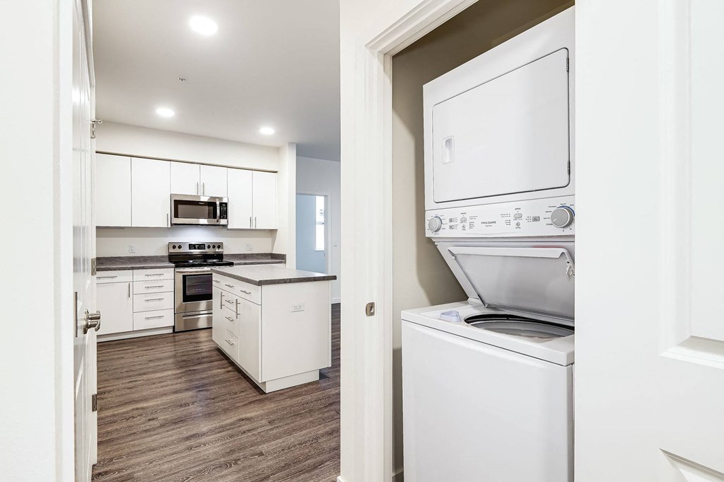 A modern kitchen with white appliances and wooden floors.