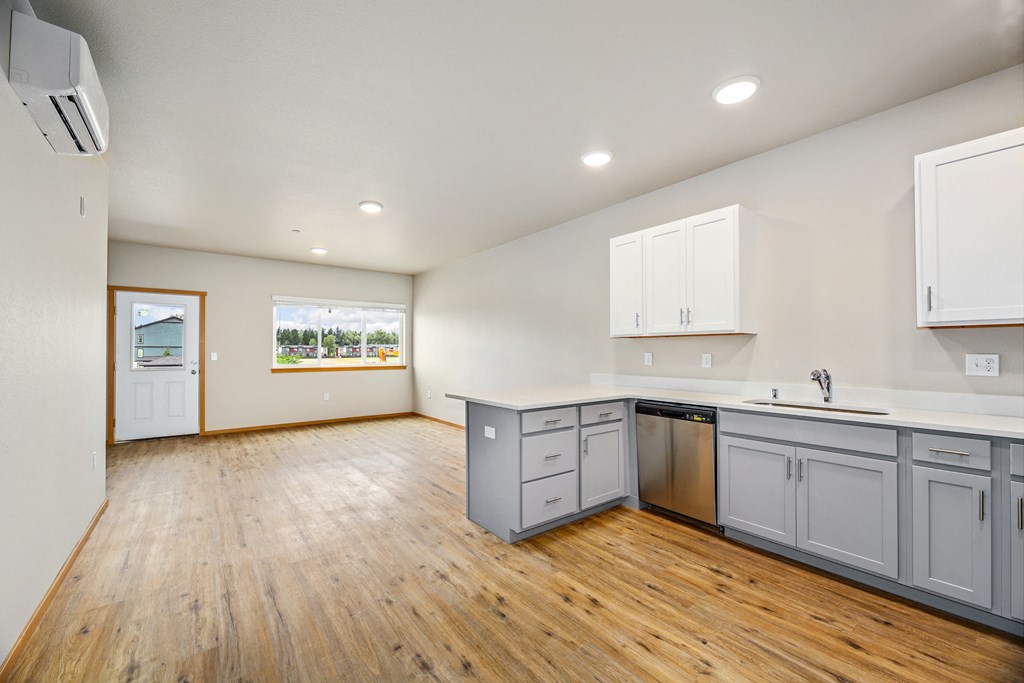 an empty kitchen and living room with white cabinets and wood floors