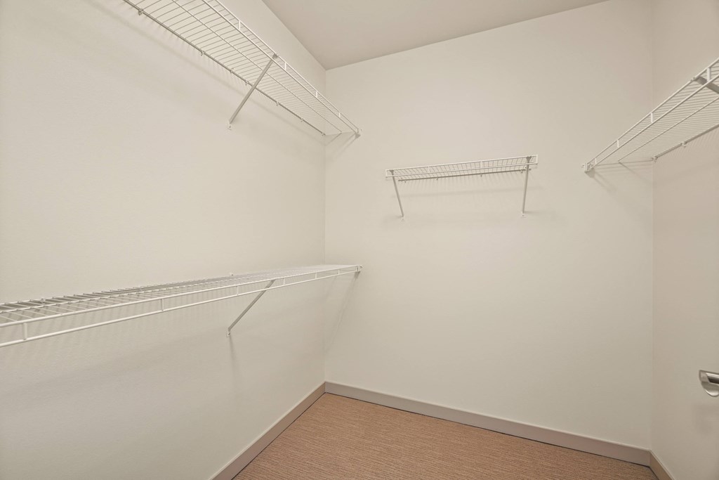 a walk in closet with two shelves and a hanging rack on the wall