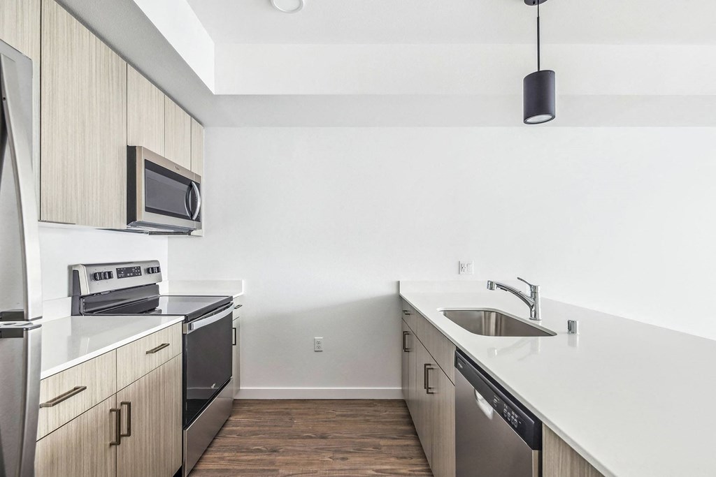 an empty kitchen with white countertops and stainless steel appliances