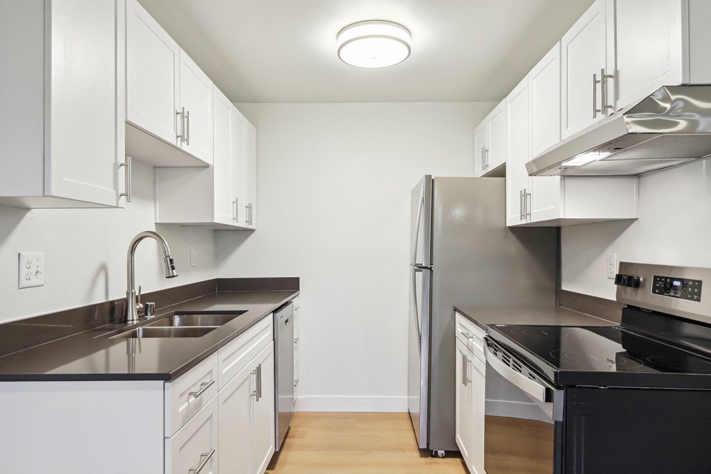 A modern kitchen with white cabinets and stainless steel appliances.