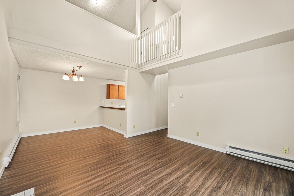 an empty living room with wood flooring and a balcony