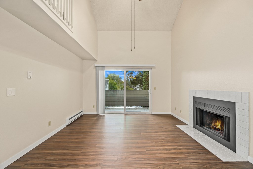 an empty living room with a fireplace and a sliding glass door