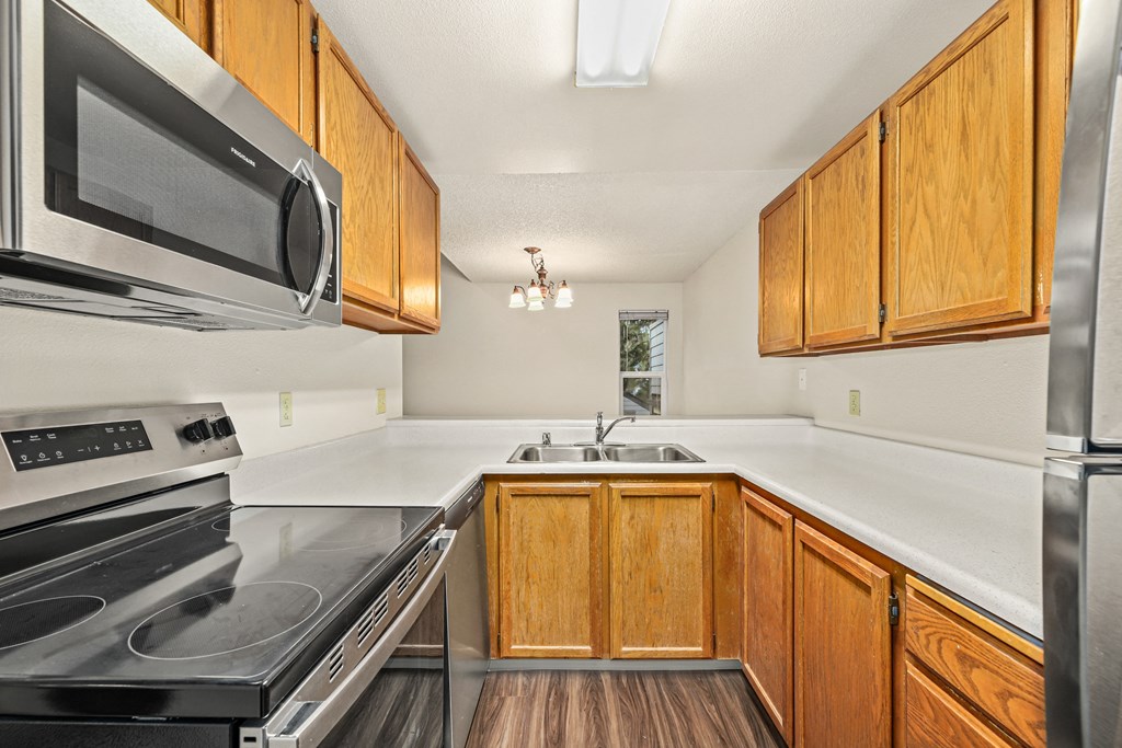 an empty kitchen with wooden cabinets and stainless steel appliances