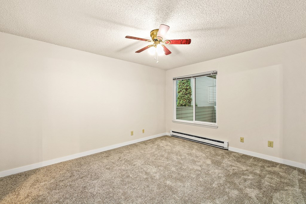 an empty living room with a ceiling fan and a window