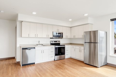 an empty kitchen with white cabinets and stainless steel appliances