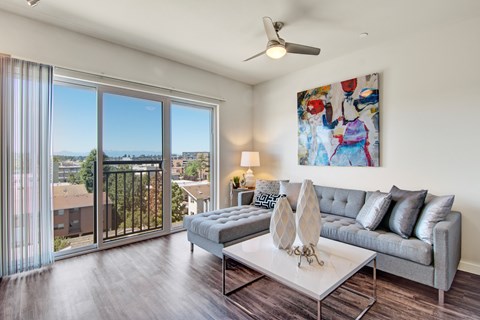 A living room with a grey couch, a white coffee table, and a painting on the wall.