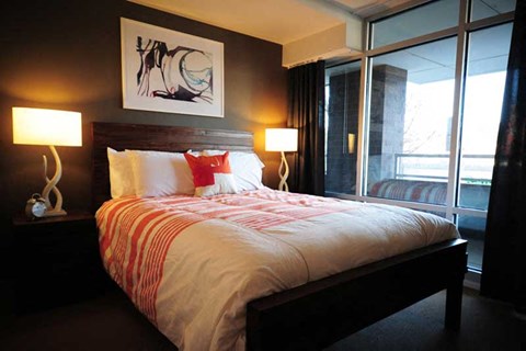 A bedroom with a large bed and two lamps.