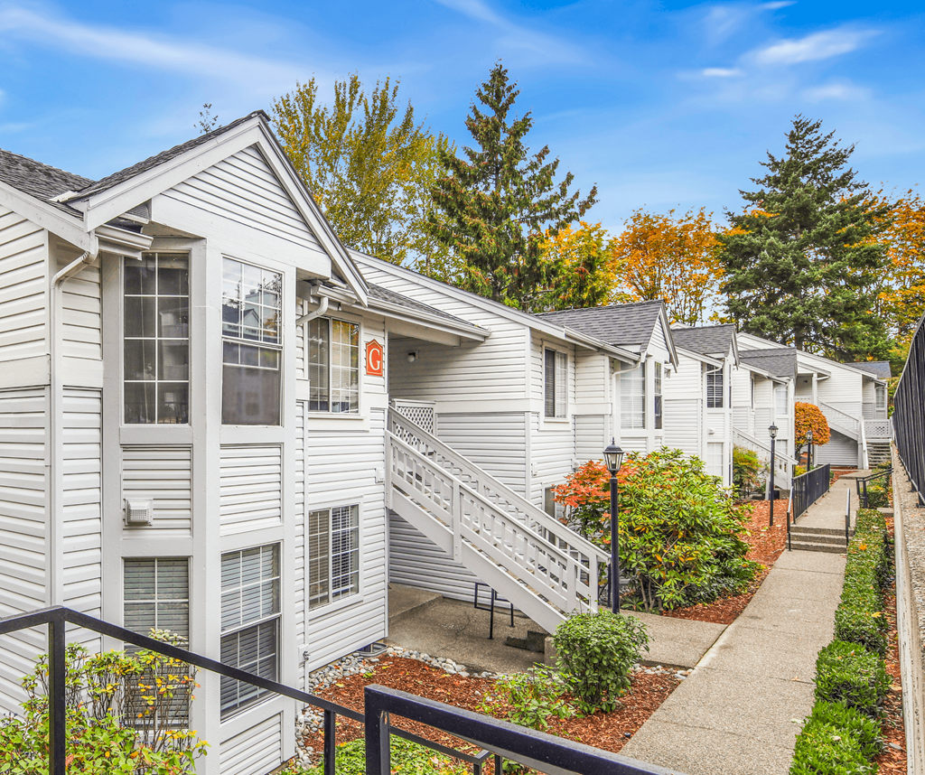 A row of white houses with a black railing in front.