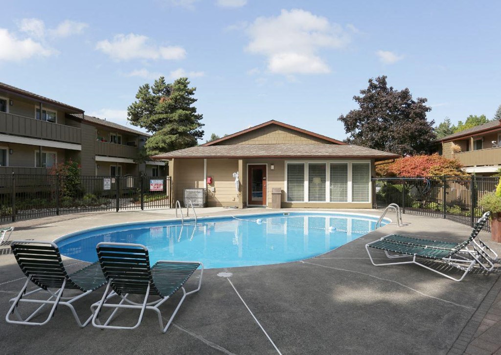 a swimming pool in front of a house with chairs