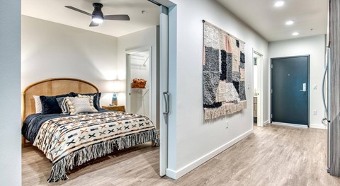 A bedroom with a bed, a ceiling fan, and a rug hanging on the wall.