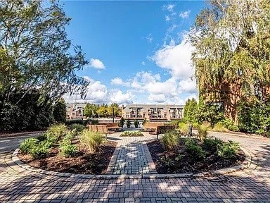 A sunny day in a park with a circular brick walkway and green trees.