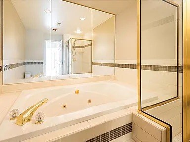 A white bathroom with a gold faucet and a gold frame around the mirror.