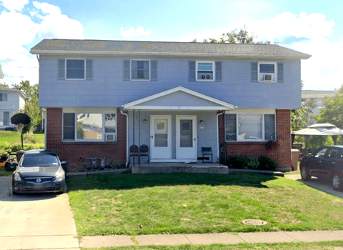A two-story house with a white door and a small porch.