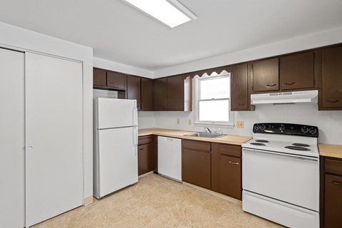 A kitchen with white appliances and brown cabinets.