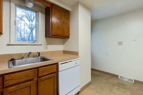 A kitchen with a white dishwasher and wooden cabinets.