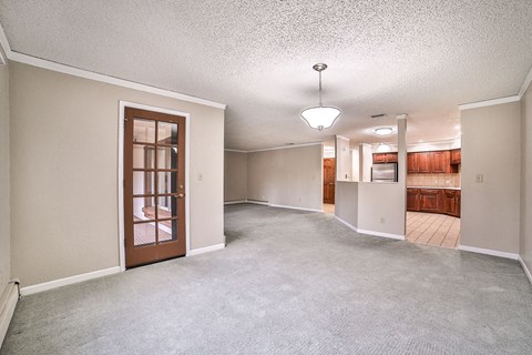 A sparsely furnished living room with a carpeted floor and a ceiling fan.