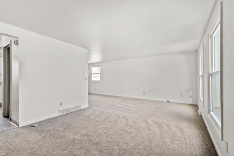 A spacious room with a carpeted floor and white walls.