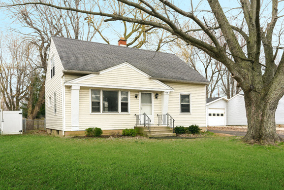 A small house with a white garage door and a black metal fence.