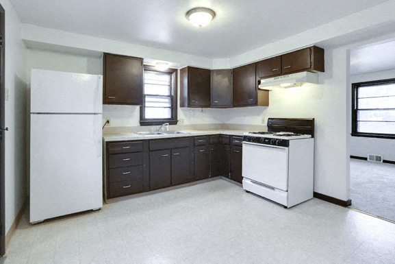 A kitchen with white appliances and dark brown cabinets.