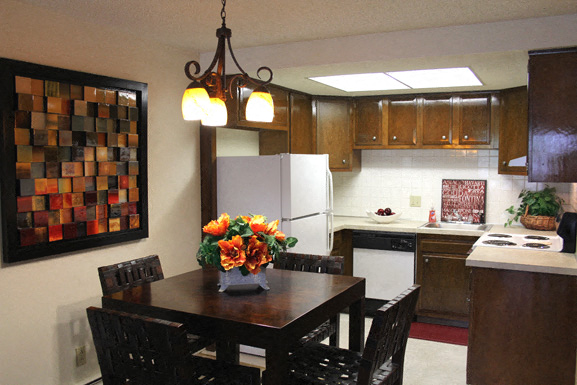 A kitchen with a table and chairs and a fridge.