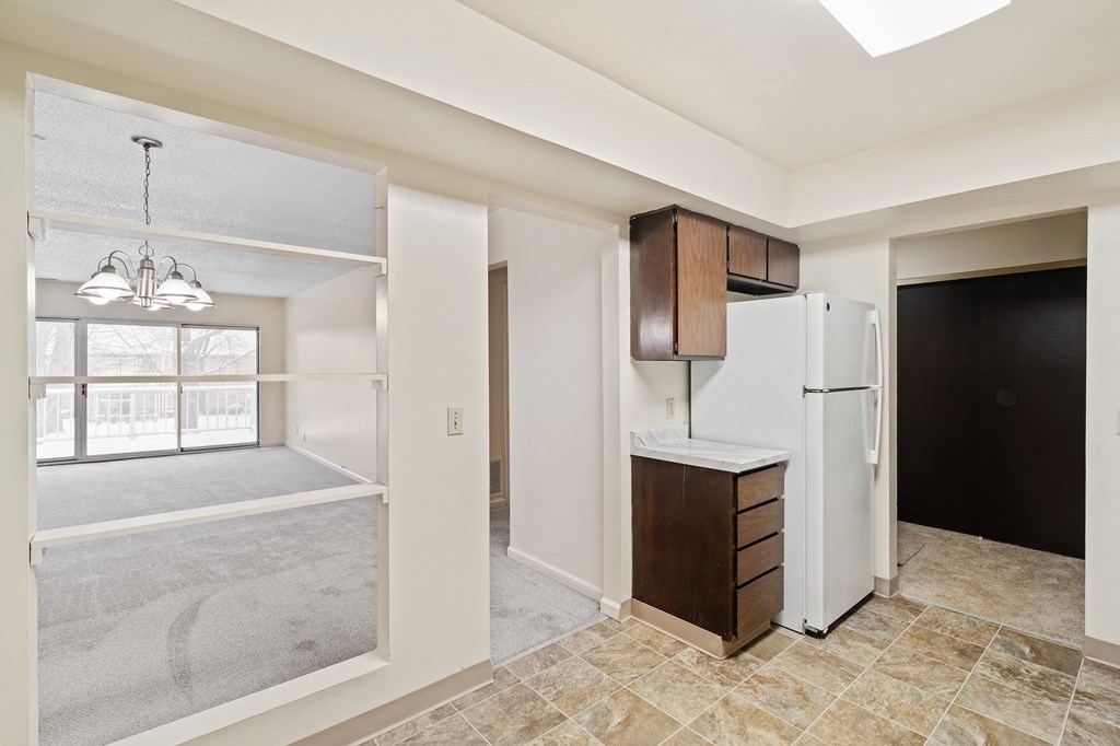 A kitchen area with a white refrigerator and brown cabinets.