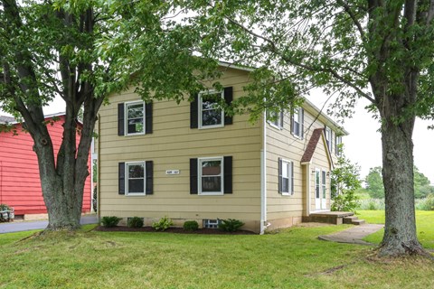 A yellow house with a red building in the background.
