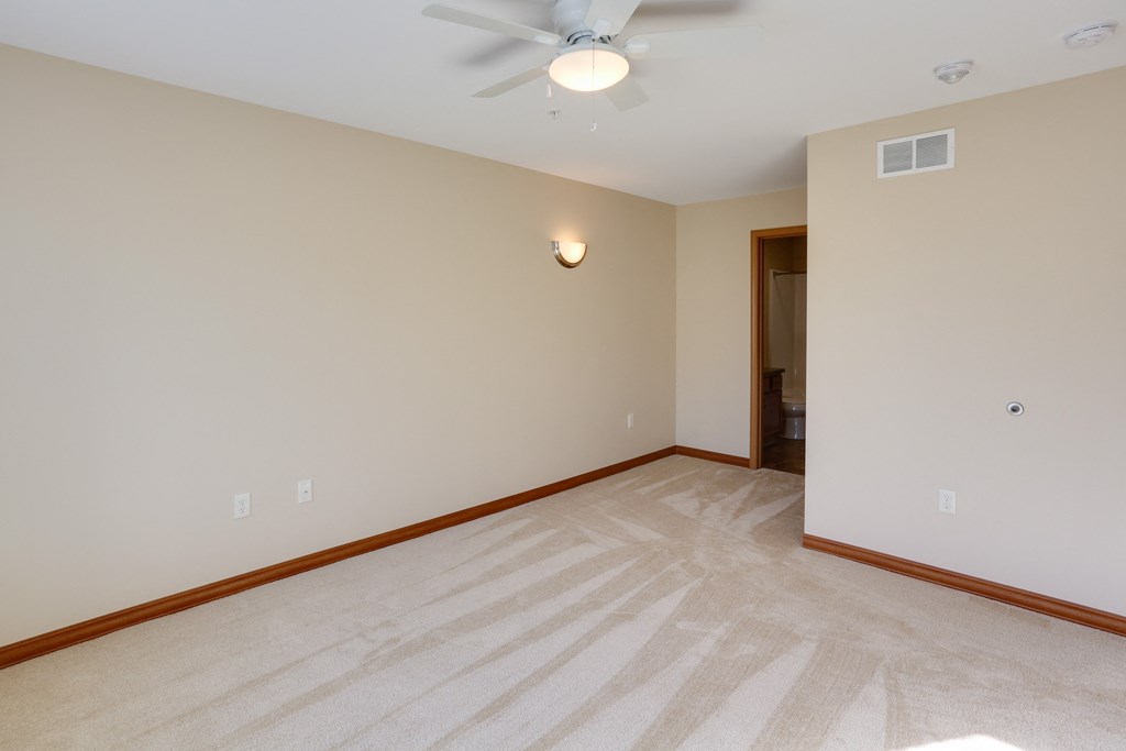 a empty living room with a ceiling fan and a white wall