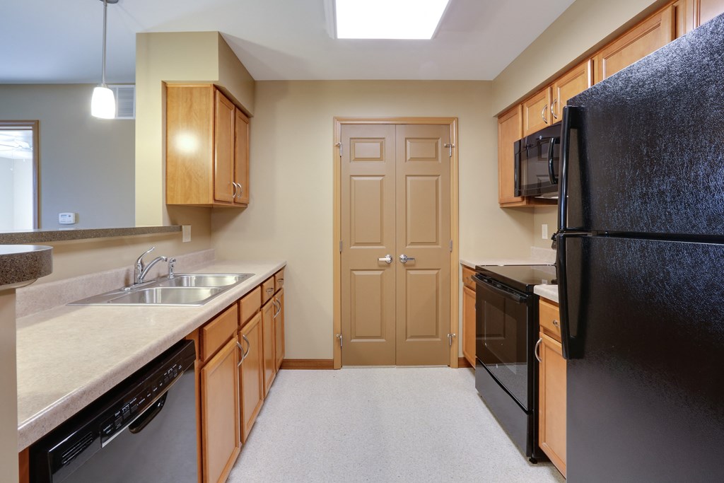 an empty kitchen with a black refrigerator and a sink