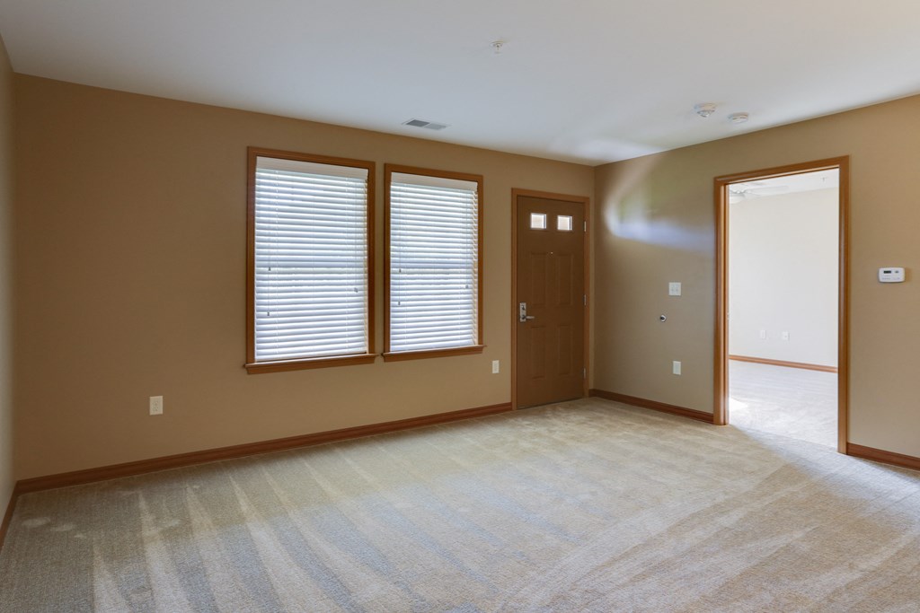 an empty living room with a door and windows