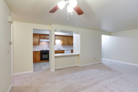 an empty living room and kitchen with a ceiling fan