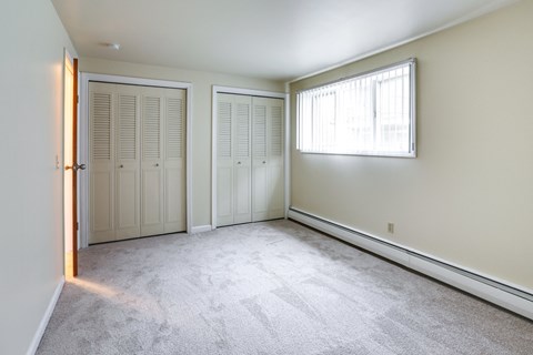 an empty bedroom with two closets and a window
