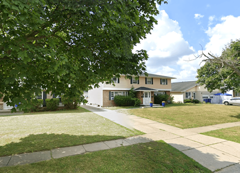 A house with a white fence and a tree in front.