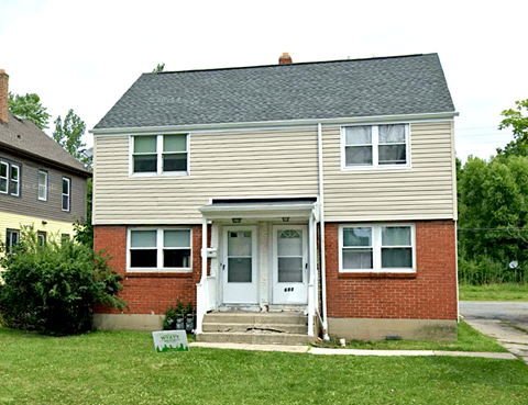 A two-story house with a white door and a sign in front that says "For Sale".