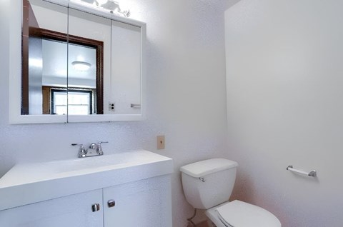 A white bathroom with a toilet, sink, and mirror.