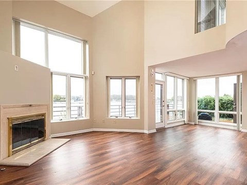 A large empty room with a fireplace and wooden floors.
