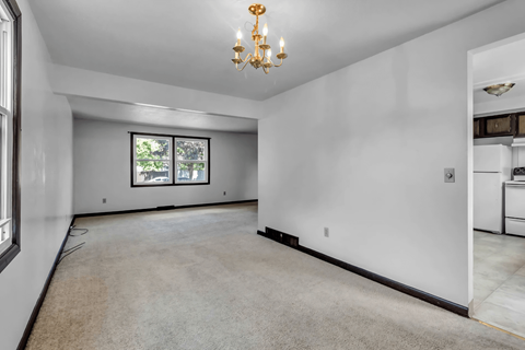 A spacious room with a chandelier and a window.