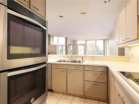 A modern kitchen with a stainless steel oven and white cabinets.