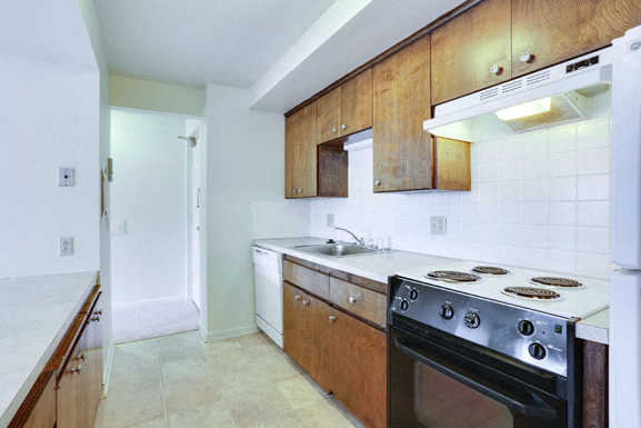 A kitchen with a white oven and wooden cabinets.