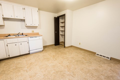 A kitchen with white cabinets and a black door.