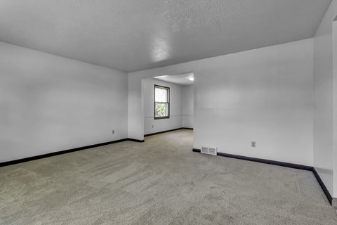 A spacious room with a carpeted floor and a window.