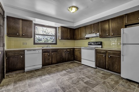 A kitchen with brown cabinets and a white refrigerator.
