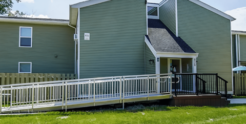 A green house with a white fence and a small porch.