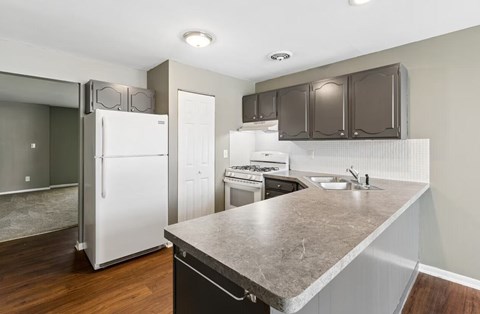 A kitchen with a white fridge and brown cabinets.