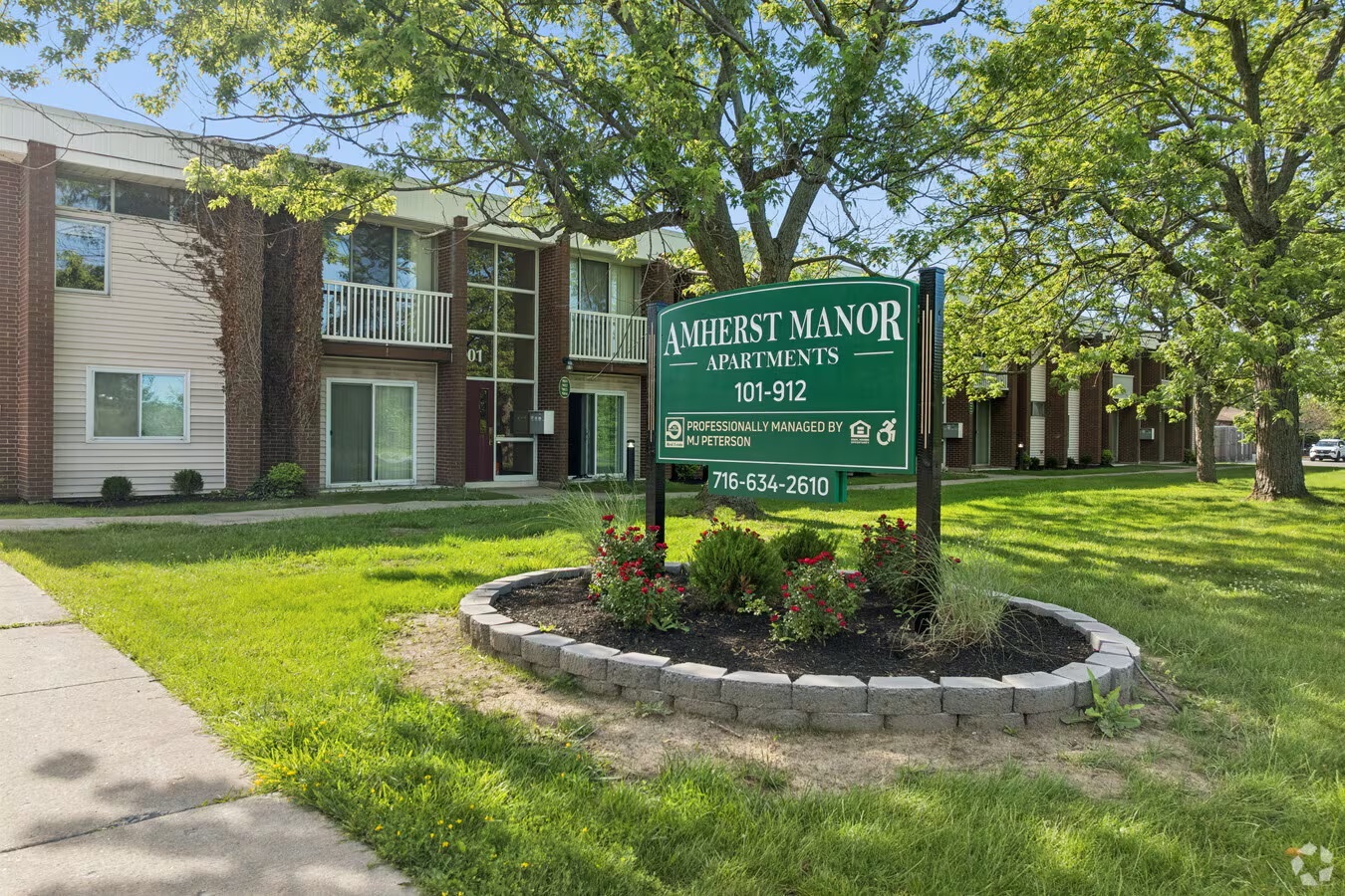 A sign for Amherst Manor Apartments stands in front of a building.