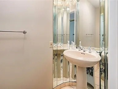A white pedestal sink in a bathroom with a mirror and a shower.
