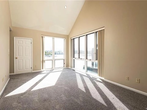 A sunny day with sunlight coming through the windows in a room with carpet flooring.