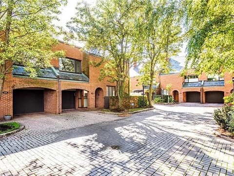 A large brick house with a driveway and trees.