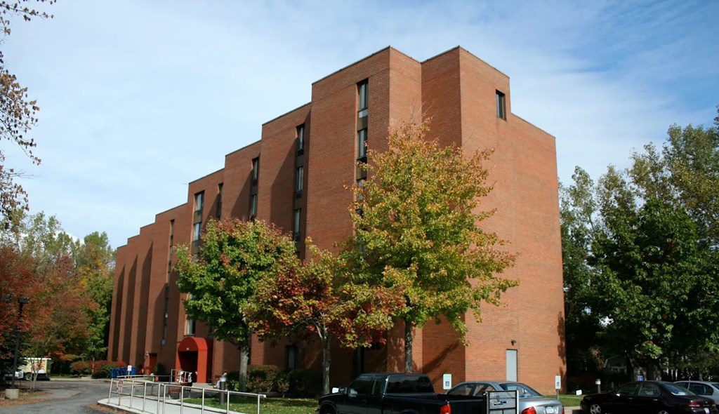 A large red brick building with trees in front.