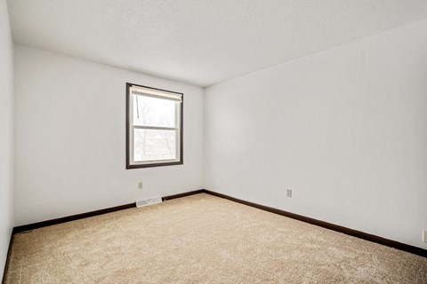 A room with a carpeted floor and a window.
